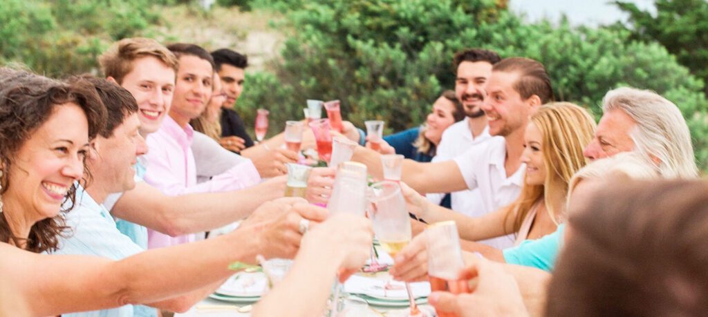 Ten people are facing each other at a long table toasting with champagne. Photo credit Dyanna LaMora