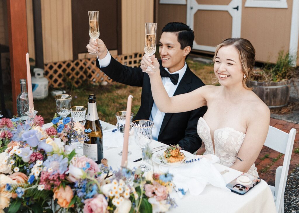 Bride and Groom raise their glasses whilst sat at their sweetheart table